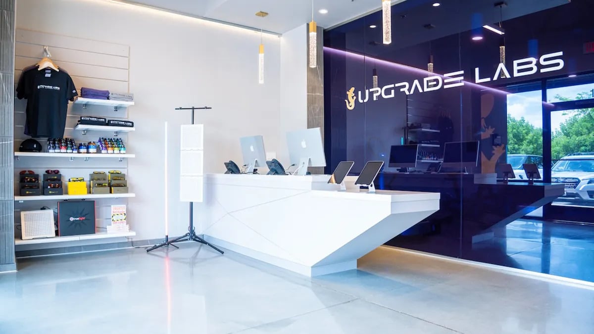 The entry way to Upgrade Labs. the wall is dark blue and the other is white. There is merchandise ready for purchase by clients and a desk for checkin.